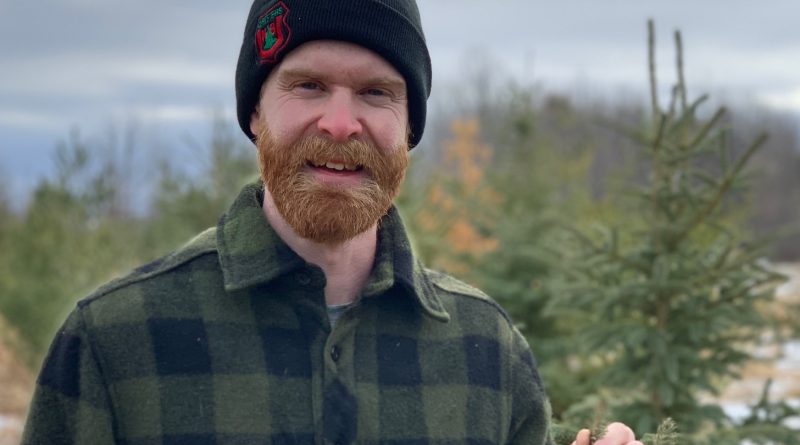 A man poses in a forest.