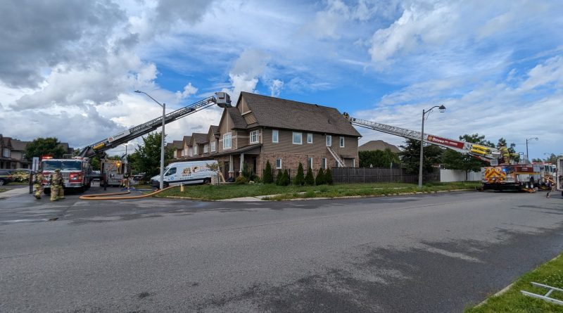 Two ladder trucks are used to fight a fire at a house.