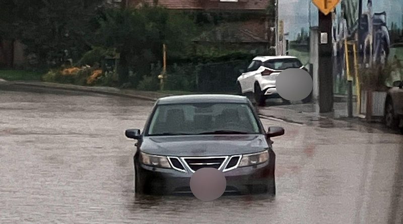 A car drives on a flooded road.