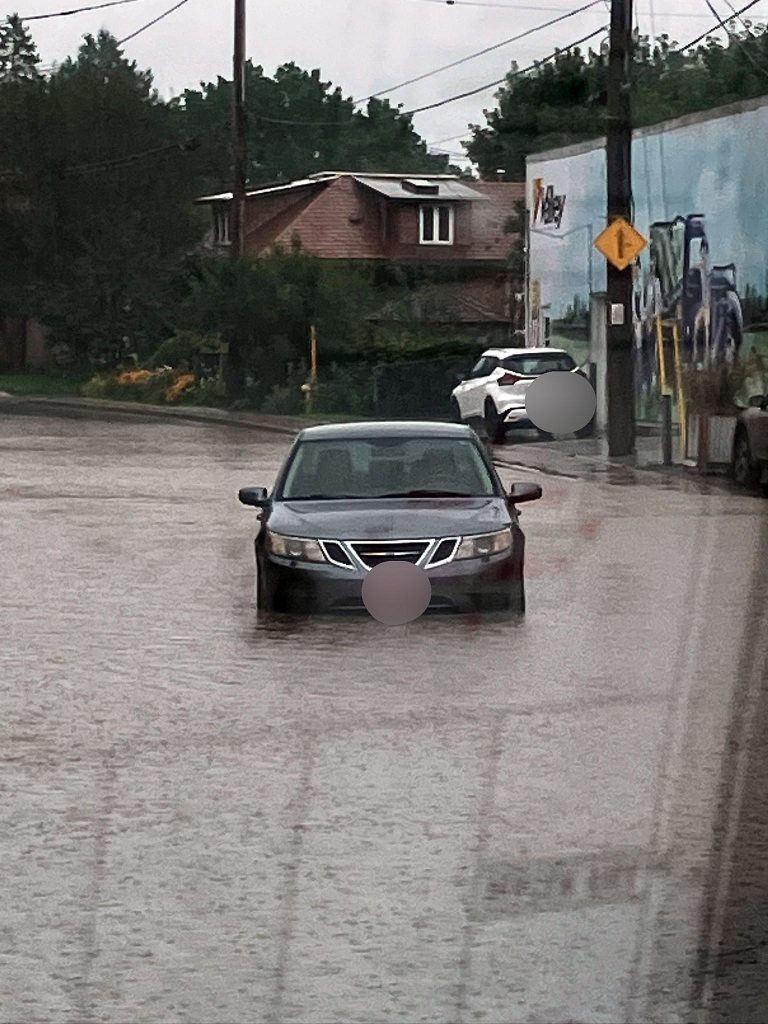 A car drives through a flooded road.