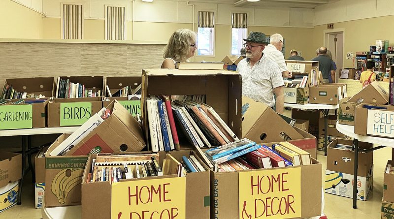 Two people talk at a book sale.