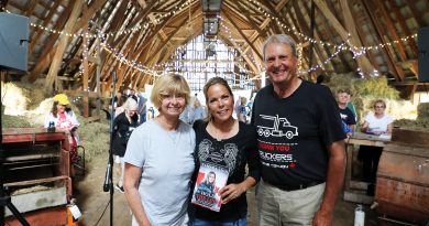 Three poeple pose in a barn.