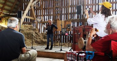 A woman speaks to a crowd in a barn.