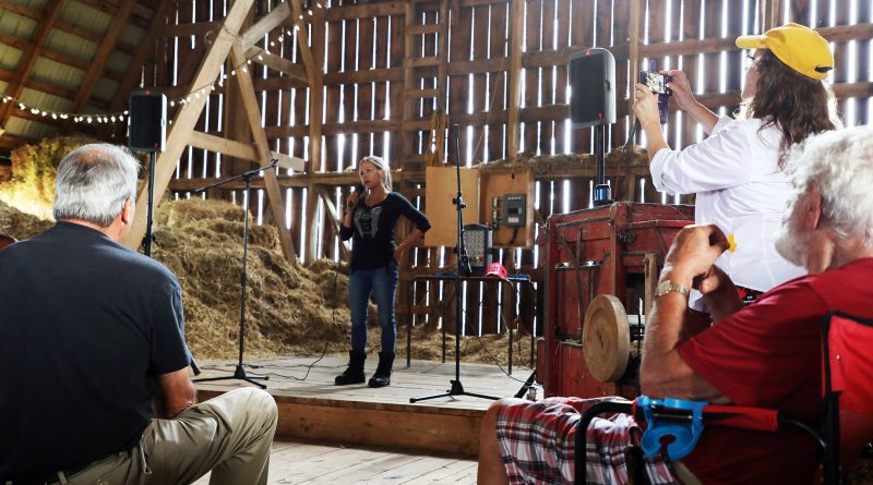 A woman speaks to a crowd in a barn.