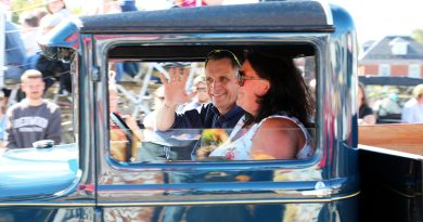 A man waves from a car.