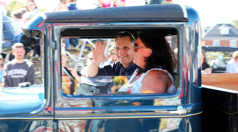 A man waves from a car.