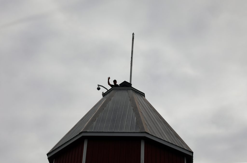 A man waves from the top of a building.