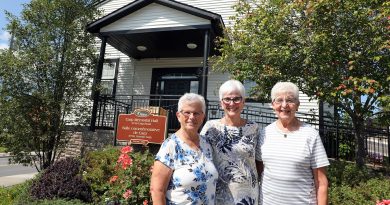 Three people pose in a garden.