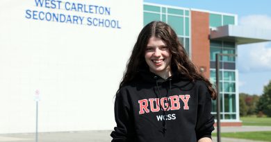 A person poses in front of a school.