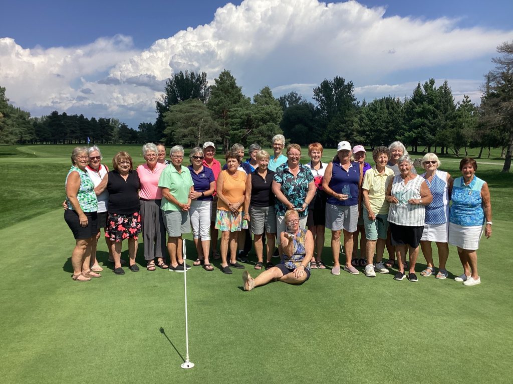 A group of ladies pose on a golf course.