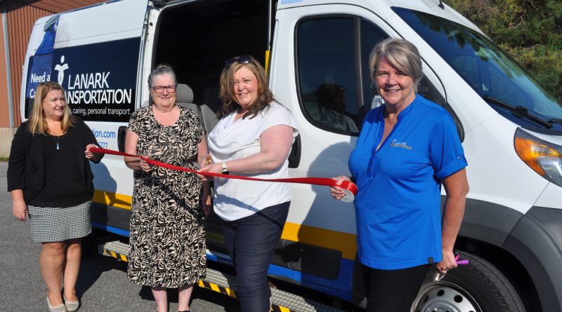 Four people pose in front of a van.