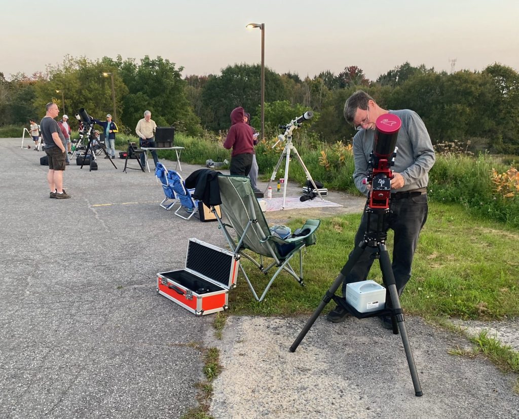 People set up telescopes in a parking lot.