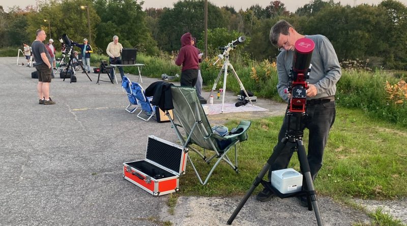 People set up telescopes in a parking lot.