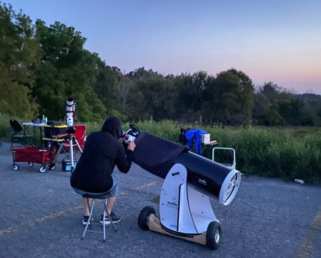 A person looks through a telescope.