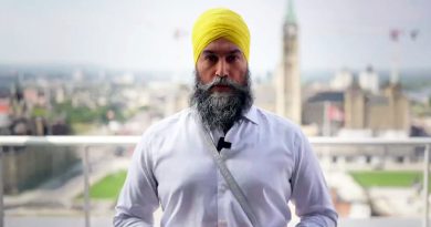 A man poses in front of the Parliament Building.