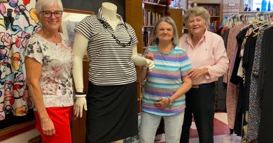 Three people pose with a headless manequin.