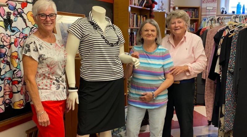 Three people pose with a headless manequin.