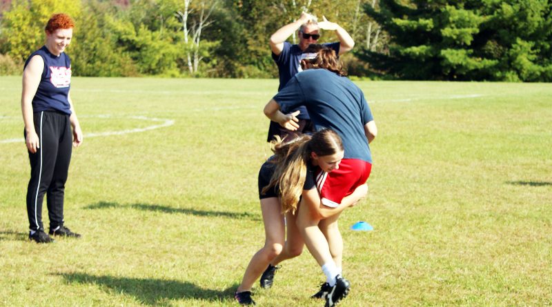 A girl tackles another girl during a rugby practice.