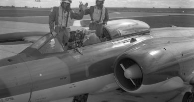 Two pilots pose on a plane.