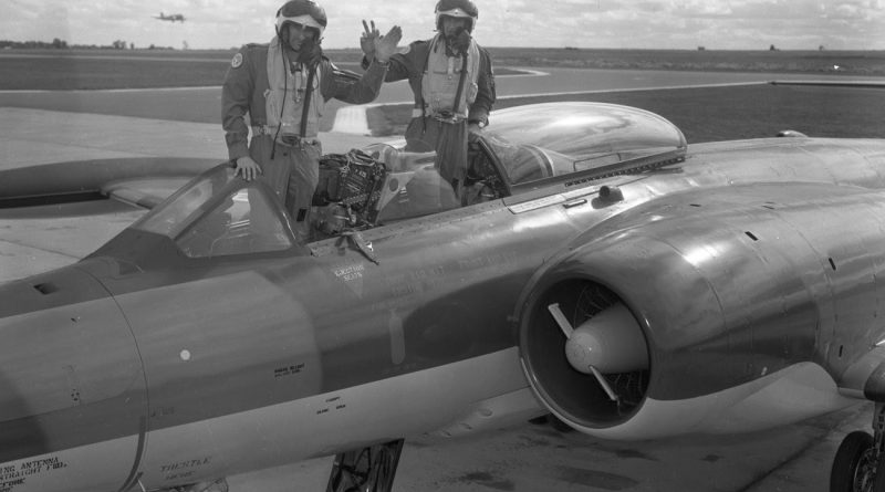 Two pilots pose on a plane.