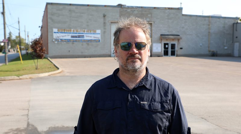 A man poses in an empty parking lot.