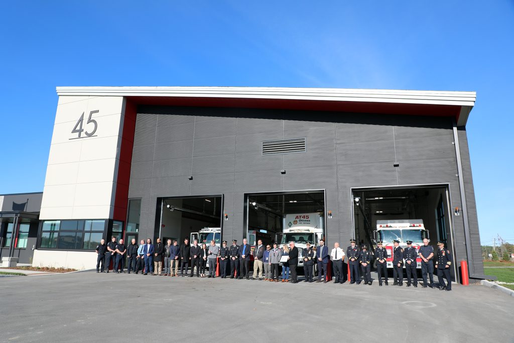 A photo of people posing in front of a fire hall.