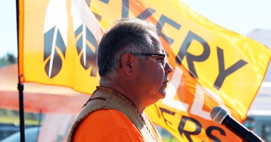 A man speaks in front of a flag.