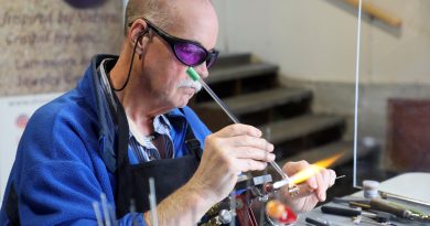 A man makes a bead with a torch.