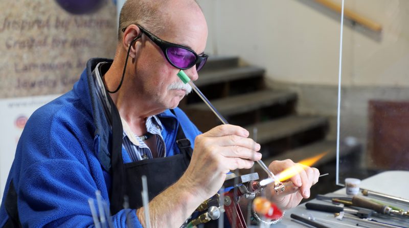 A man makes a bead with a torch.