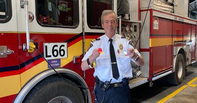 A firefighter poses in front of a fire truck.