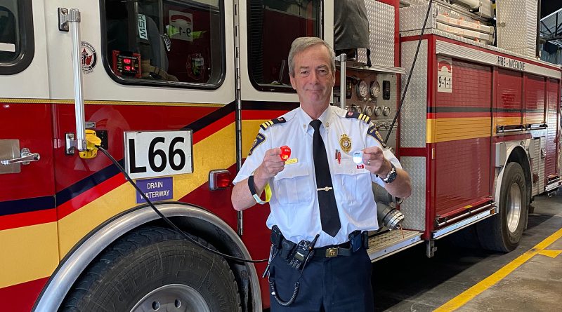 A firefighter poses in front of a fire truck.