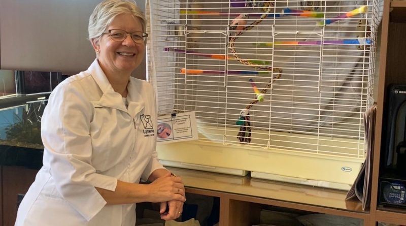 A vet poses beside a bird.