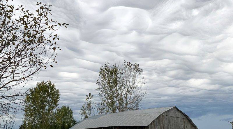 A photo of clouds over a barn.