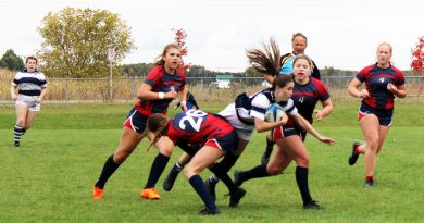 A girl tackles another girl in a rugby game.