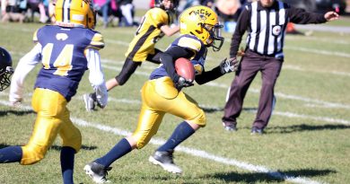 A football player runs with a football.