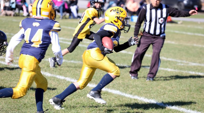 A football player runs with a football.