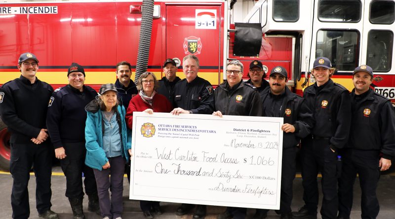 A group of firefighters and food bank volunteers pose for a photo.