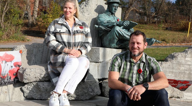 Two people pose on a statue.