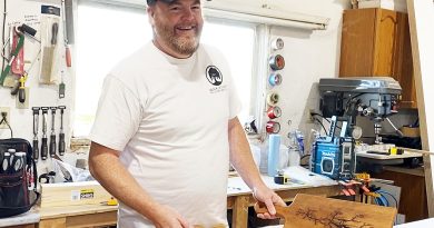 A woodworker poses with some of his work.