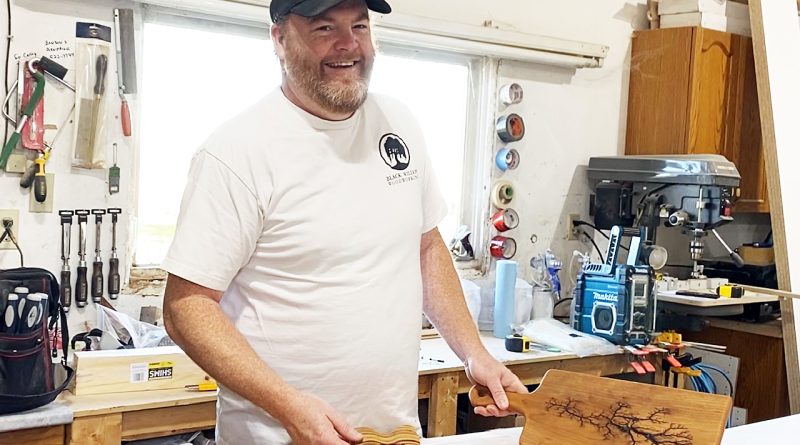 A woodworker poses with some of his work.