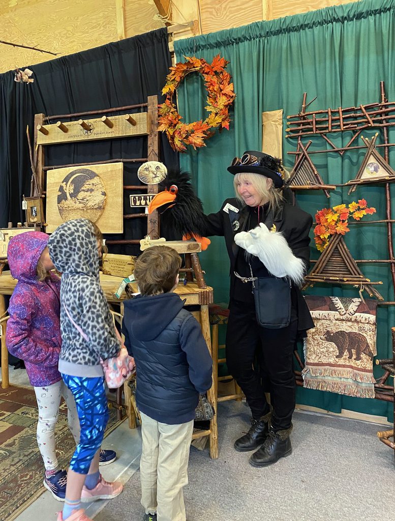 A woman shows some kids a puppet.