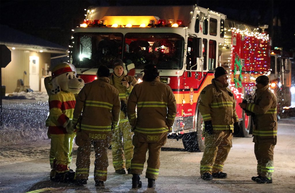 Firefighters pose in front of a flashing truck.