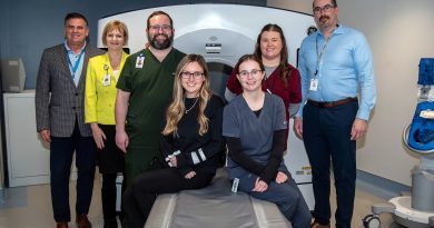 A group poses around a CT scanner.