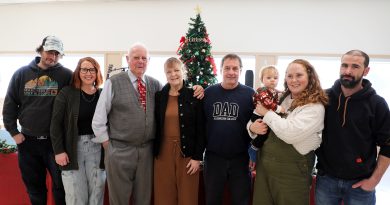 A family poses in front of a Christmas tree.