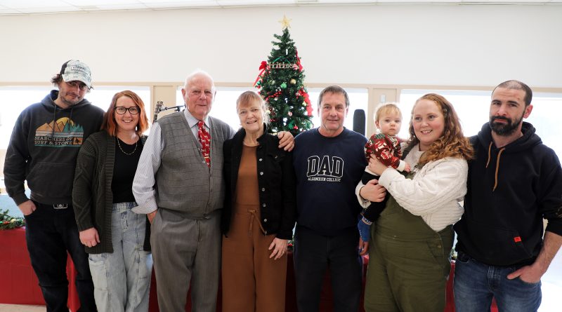 A family poses in front of a Christmas tree.