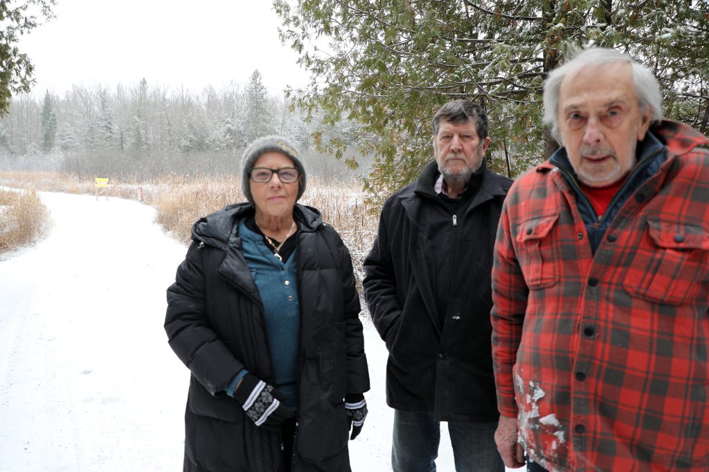 Three people pose on a road.