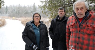 Three people pose on a road.