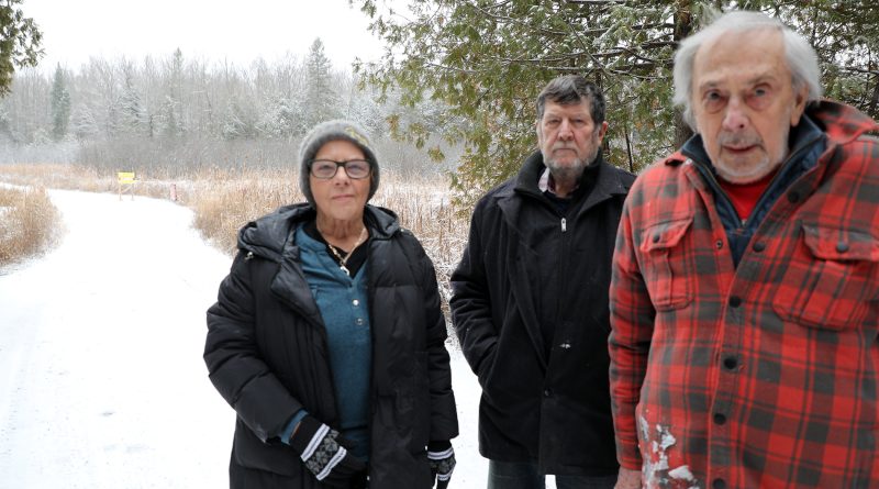 Three people pose on a road.