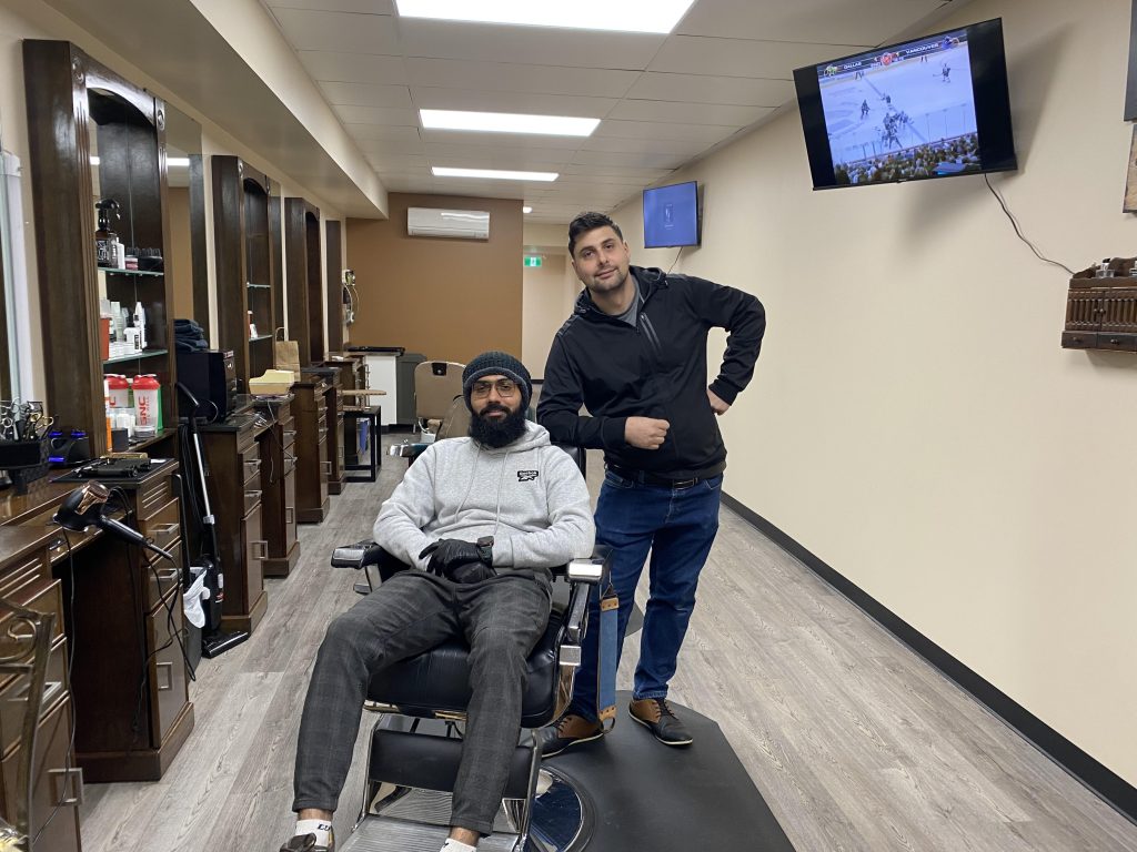 Two people pose in a barber shop.