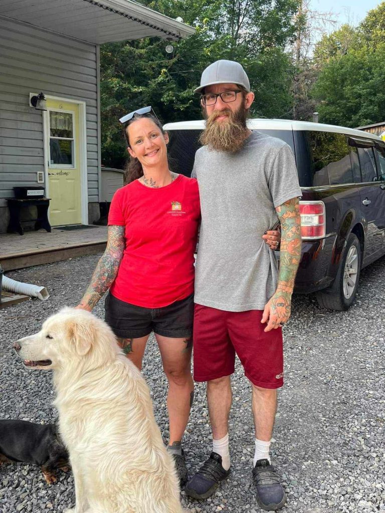 Two people pose with a dog.